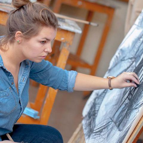 Woman working on a charcoal drawing